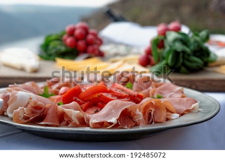 Platter with cured ham on table, radish in the background