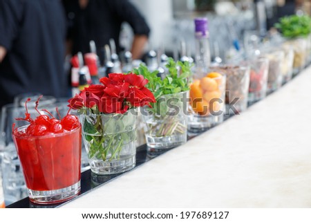 Cocktail cherries, herbs and rose flowers on bar counter