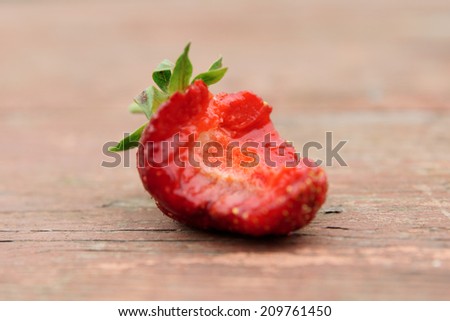 Strawberry with missing bite on wooden table