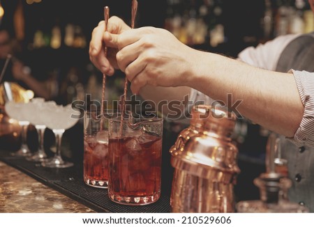 Bartender is stirring cocktails on bar counter, toned image