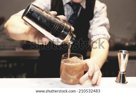 Bartender is making cocktail at bar counter , toned image