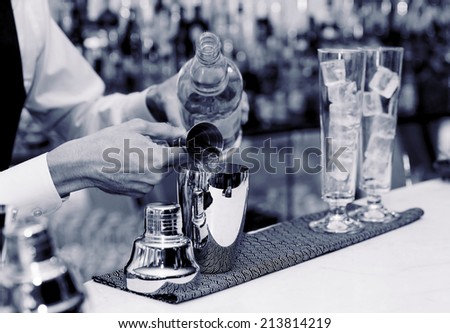 Bartender is pouring liquor in shaker, blue toned