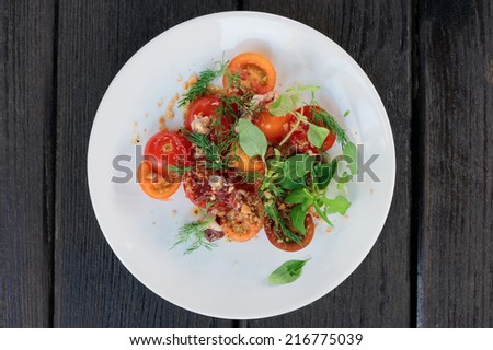 Appetizer with cherry tomatoes and smoked duck fillet on black wooden surface