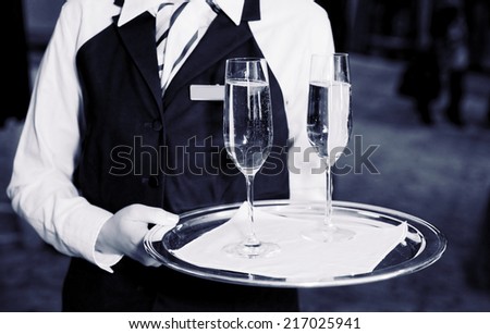 Female waiter welcomes guests with champagne, toned image