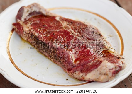 Striploin steak with black pepper and oil, shallow depth of field