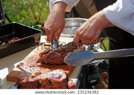 Chef is cutting meat at outdoor kitchen