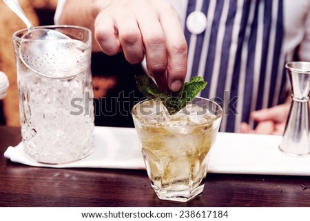 Bartender is making cocktail at bar counter, toned