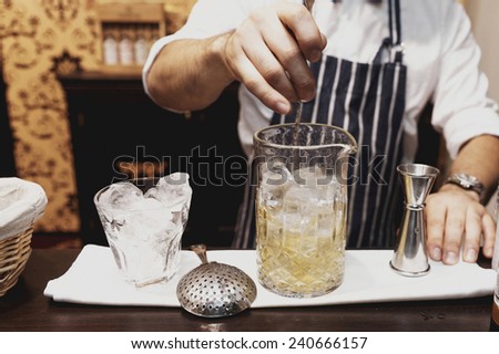 Bartender is making cocktail at bar counter, toned