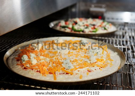 Cheese pizza entering the industrial oven, close-up