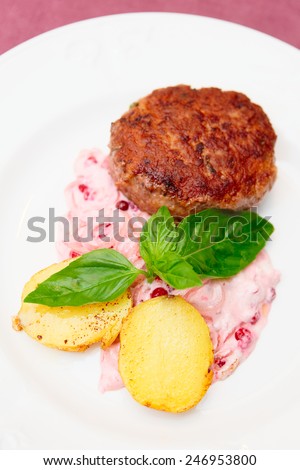 Beef patty cake with creamy sauce and potatoes on plate