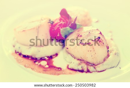 Scallops with potato mash on a porcelain plate, toned image