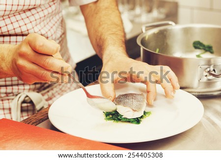 Chef is serving steamed seabass with spinach, toned image