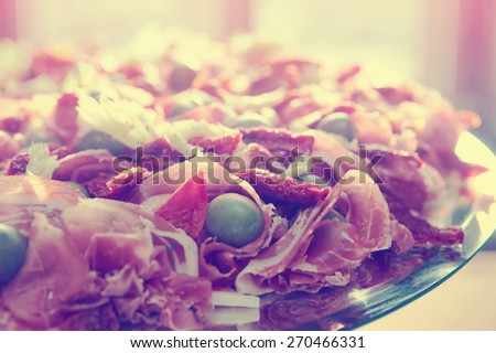 Platter with spanish cured ham on table, toned image