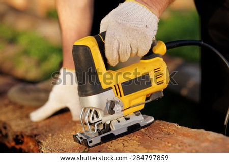 Carpenter is cutting wood with fret saw, outdoor shot, reality shot