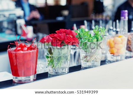 Cocktail cherries, herbs and flowers on bar counter