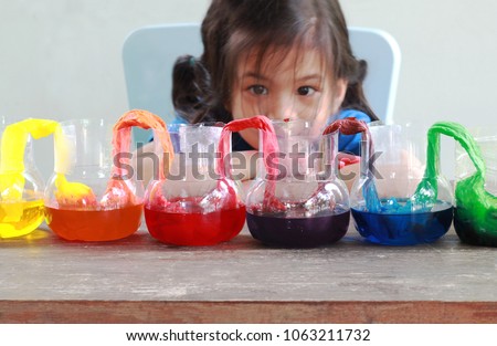 Fun and easy science.5 years old Asian girl making Walking Water experiment.Food color add to the water in the recycled bottle,water moving along the paper then color mixed.Concept of science for kid