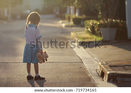 5 year old Asian little girl stand alone at the street,lonely with her doll.Loneliness is common when kid start pre-school or big life changes.Kid have no friends ,they say that nobody likes them.