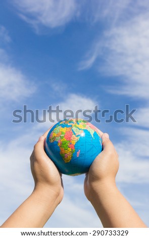 hands holding globe with sky background
