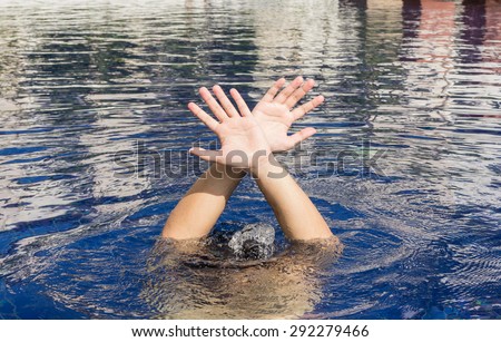 Hand of drowning man in a swimming pool