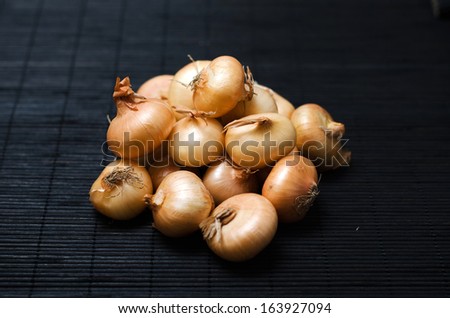Small heap of golden onions on dark background