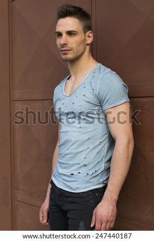Young man standing against red metal doors. Athletic build