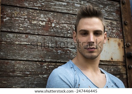 Young man portrait against old wood wall. Looking at camera