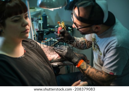 ROME - MAY 11: Tattoo artist draws with his tattoo machine on client's arm a compass rose design in his workshop on May 11, 2014 in Rome