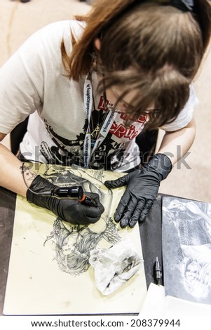 ROME - MAY 11: Tattoo student practices with his tattoo machine on fake human skin in his workshop on May 11, 2014 in Rome