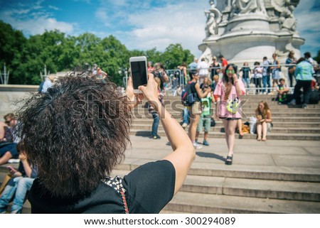 LONDON, UK - JULY 10: Tourist take a picture of friend near the Victoria Memorial, Buckingham Palace, London on 10 July 2015
