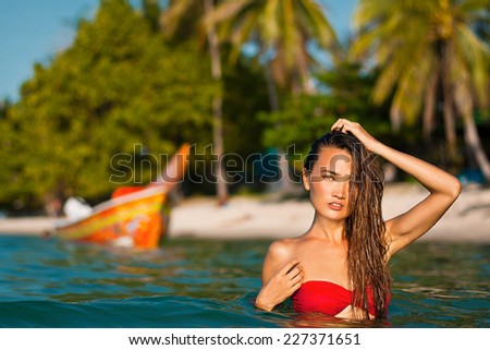 Beautiful asian girl in a sea in red bikini