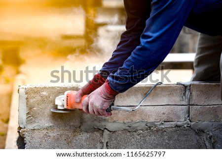 Worker cutting concrete concept, cutting concrete machine on brick block wall by workman in industry site of building structure. He wearing glove for protect and safety for working in this site