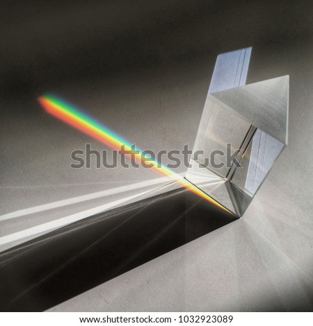 Sunlight through prism on dark background scattering rainbow spectrum, shadow and light shapes