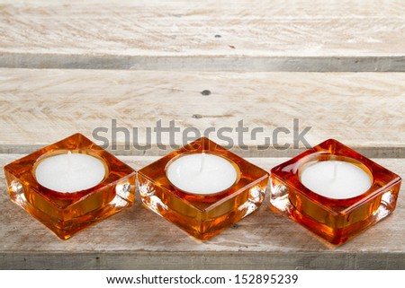 Three new candles in candle holders on wooden surface