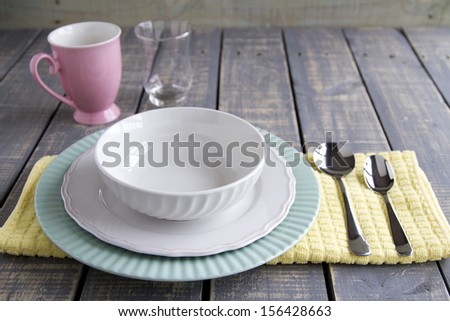 Bowl, plates and spoons on a cloth with glass and mug on wood table