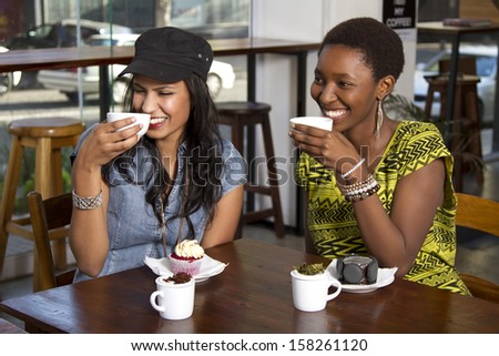Two beautiful girlfriends having freshly brewed tea in a coffee shop