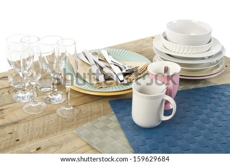 Cutlery, crockery, place mats and glasses ready to be set for a meal