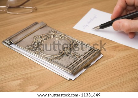 writing note near vintage silver notebook cover with patina for paper storing