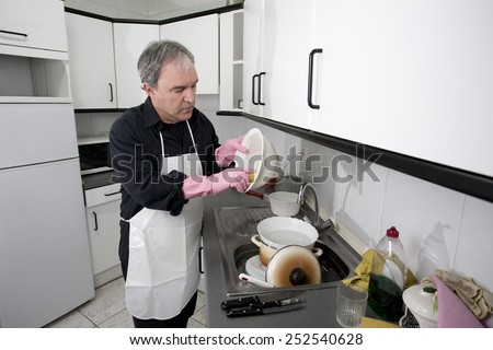 Man cleaning the dishes in the kitchen sink