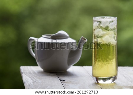 With long green ice tea and glass teapot on unfocused background