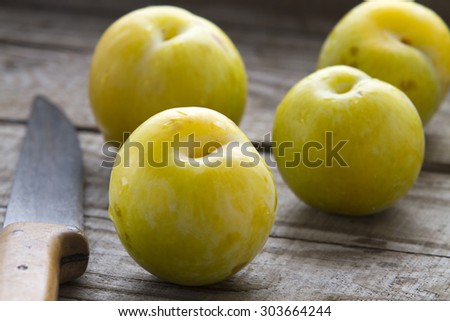 Yellow plums and knife on table rustic background