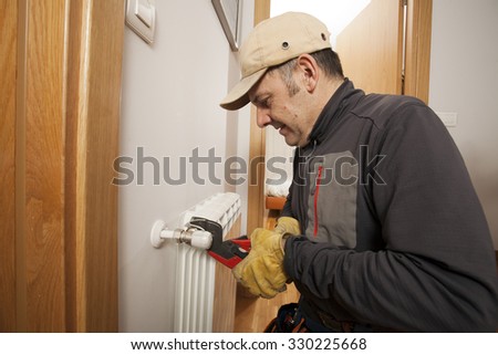 Plumber fixing a radiator in a house