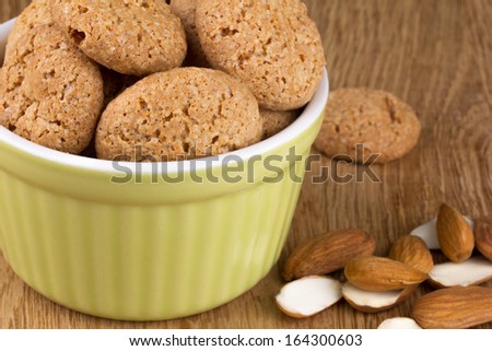 almond cookies in a ceramic dish with almonds on a wooden tray