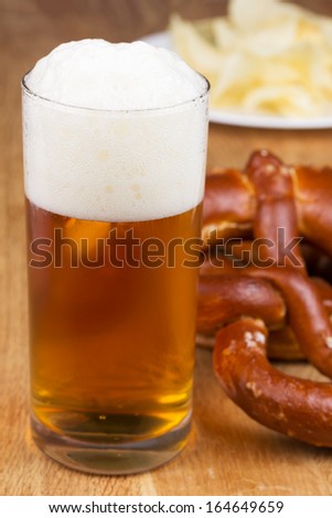 Typical crusty german pretzel bread with beer and chips in the background