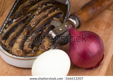 sprats in a tin with red onion, boiled egg and opener