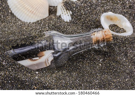 message in a bottle on the sand with shells of mollusks