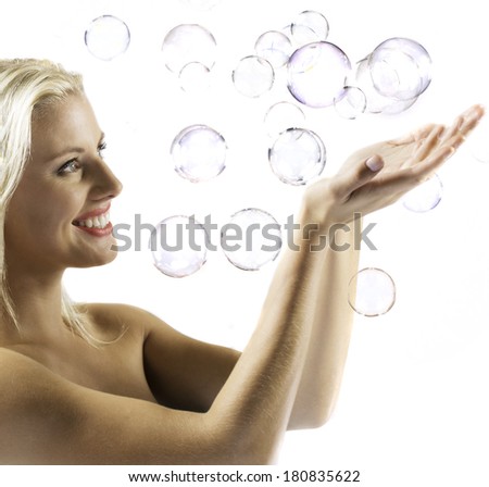 An attractive young woman attempts to catch floating bubbles./Bubbles
