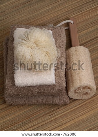 Towels folded, sea sponge and scrubby on natural straw mat.