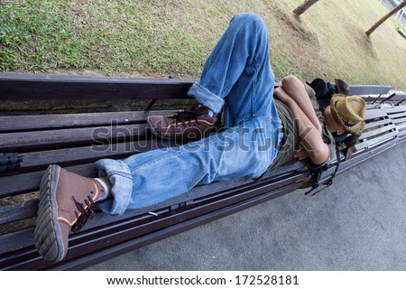man is  sleeping on a chair in the park