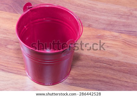 red miniature metal bucket, isolated on wood