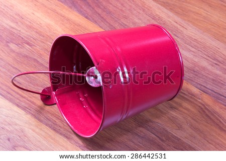 red miniature metal bucket, isolated on wood